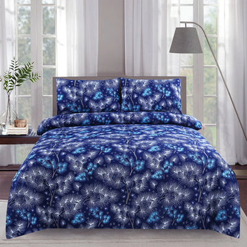 Blue floral patterned bedding set on a bed with a lamp and plant in the background.