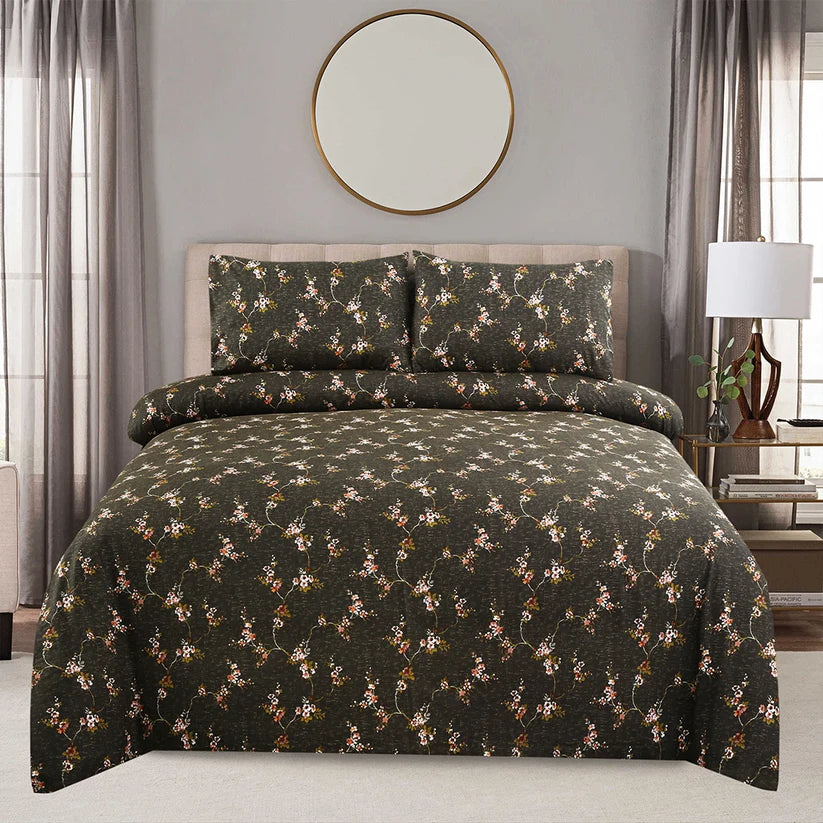 Floral patterned bedding set on a bed in a bedroom with curtains and a lamp.