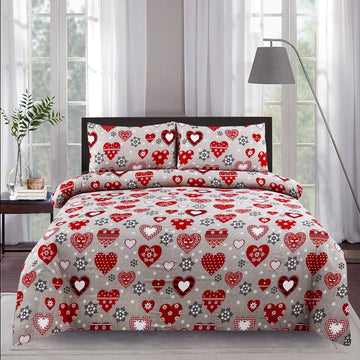 Heart-patterned bedding set on a bed in a bedroom with curtains and a lamp.