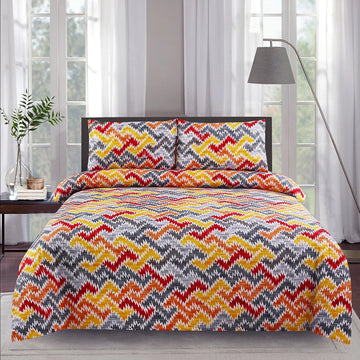 Bed with colorful zigzag pattern bedding set in a room with large windows.