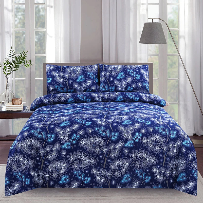 Blue floral patterned bedding set on a bed with a lamp and plant in the background.
