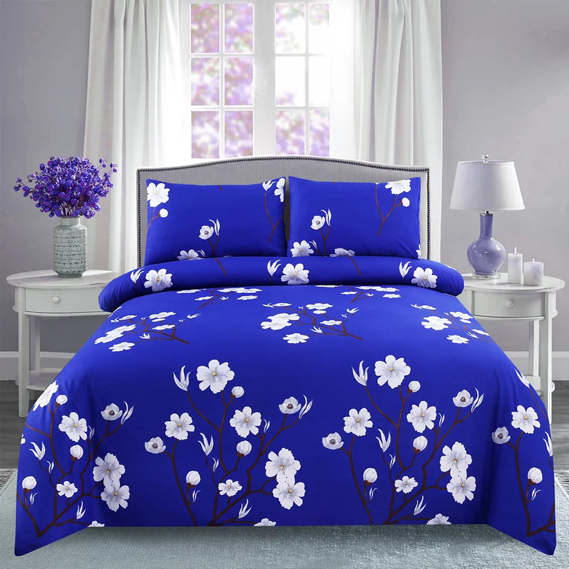 Blue floral comforter set on a bed in a bedroom with white curtains and side tables.
