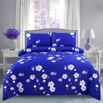 Blue floral comforter set on a bed in a bedroom with white curtains and side tables.