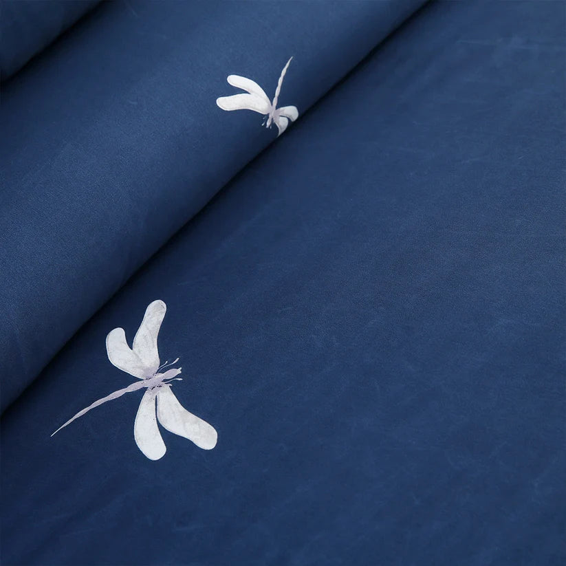 Navy blue floral bedding set on a bed in a room with white walls and framed pictures.