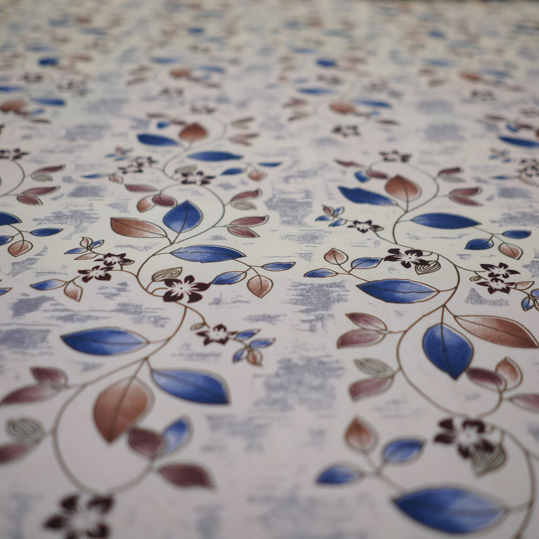 Floral patterned bedding set on a bed with matching pillows and a lamp in the background.