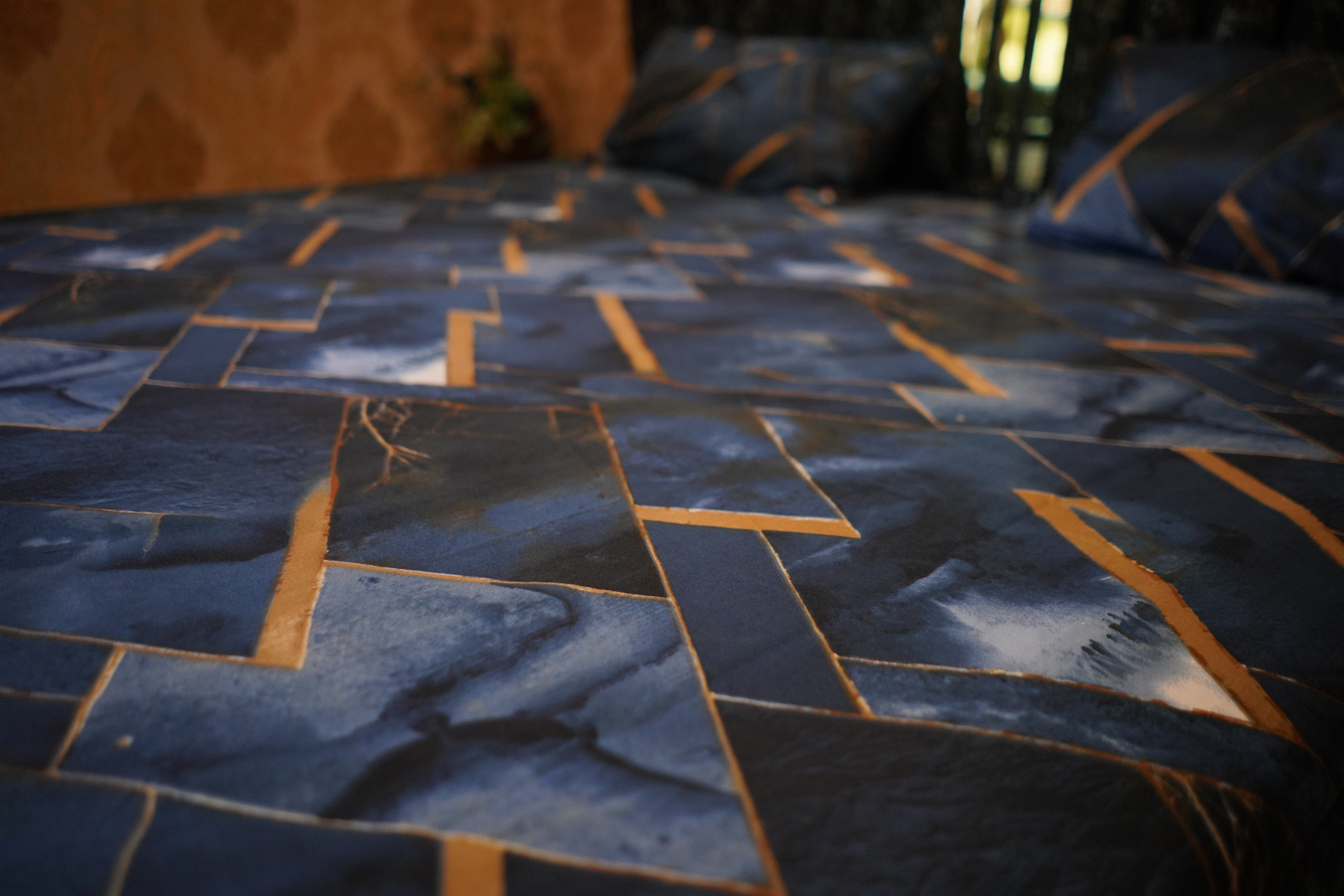 Blue quilt with geometric pattern on a bed