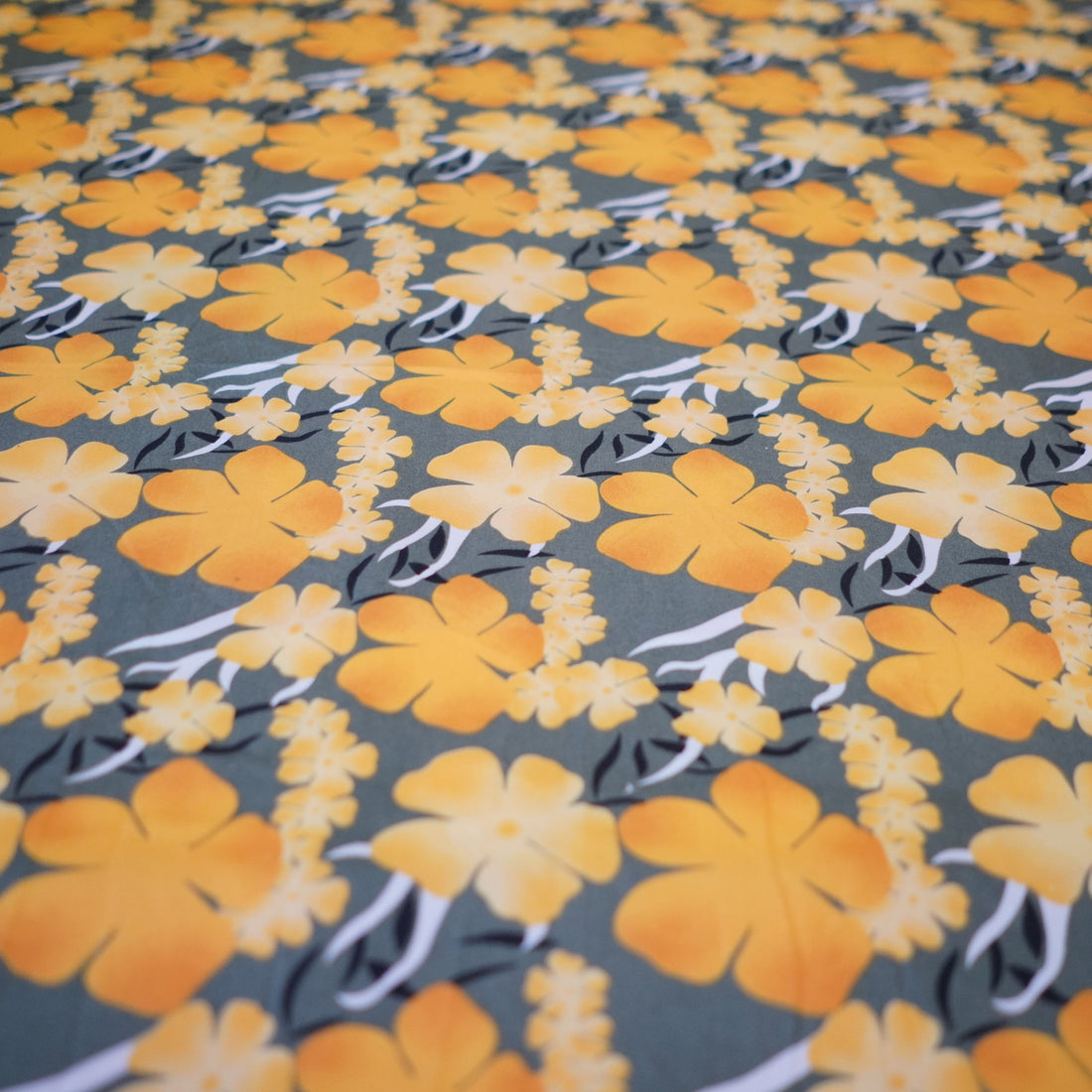 Floral fabric with yellow flowers and black leaves on a gray background