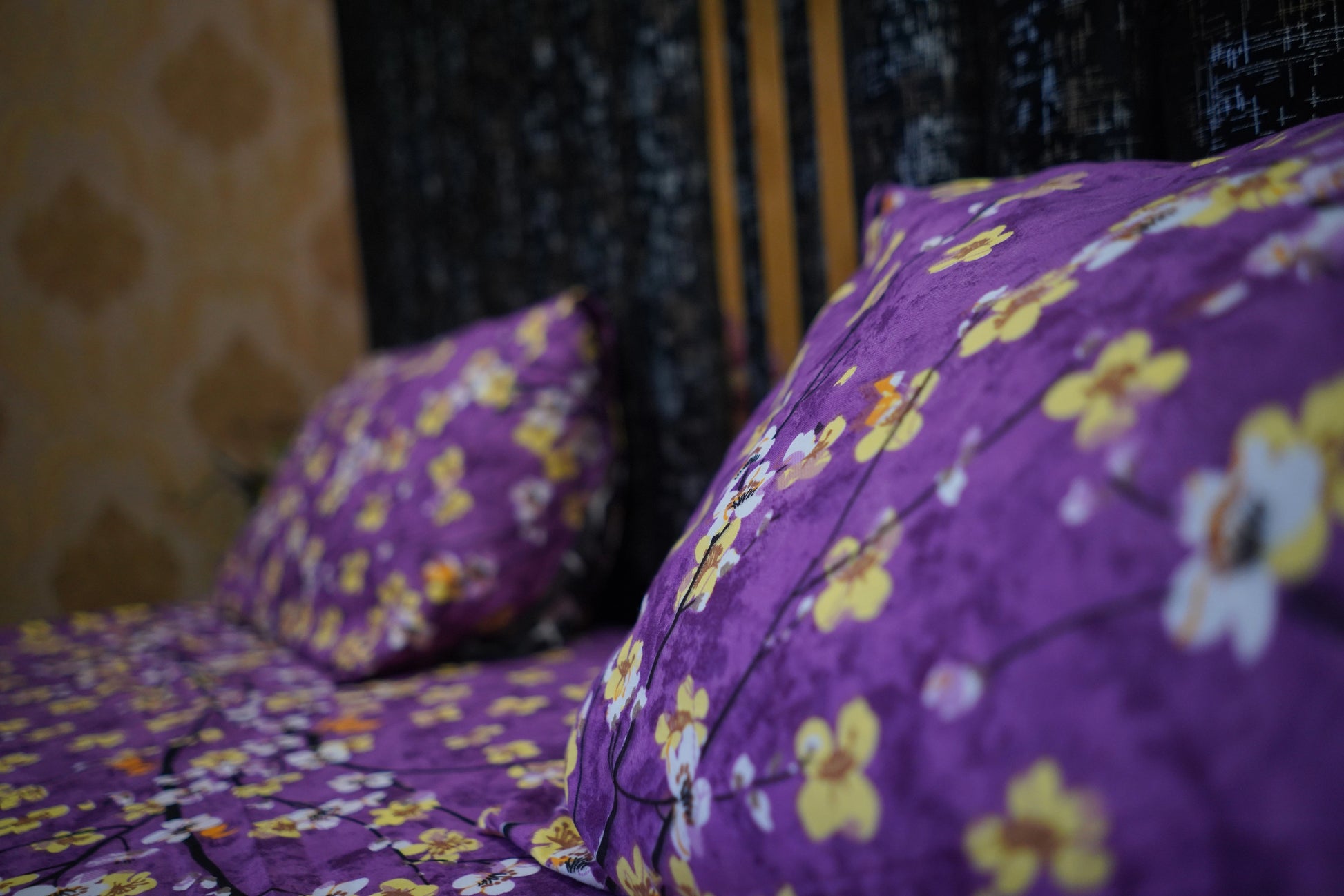 Purple floral bedspread on a bed with a blurred background