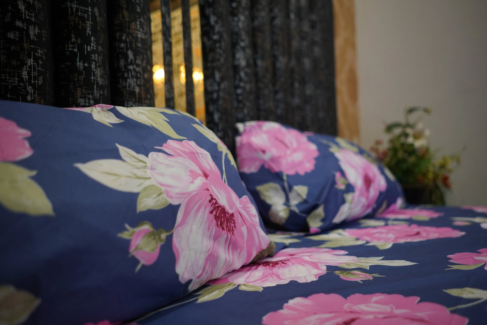 Floral patterned pillows and bedspread on a bed with a blurred background