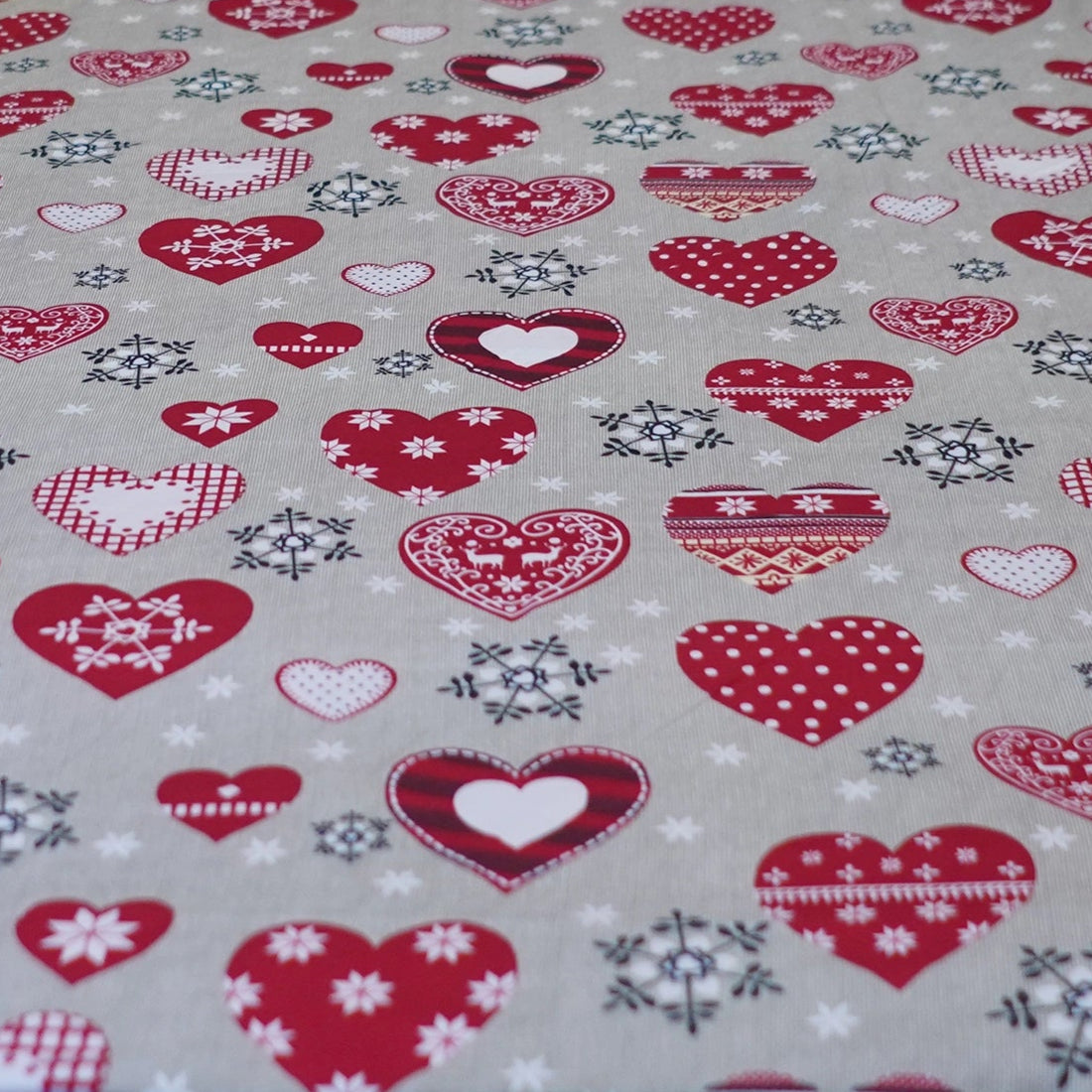 Heart-patterned bedding set on a bed in a bedroom with curtains and a lamp.