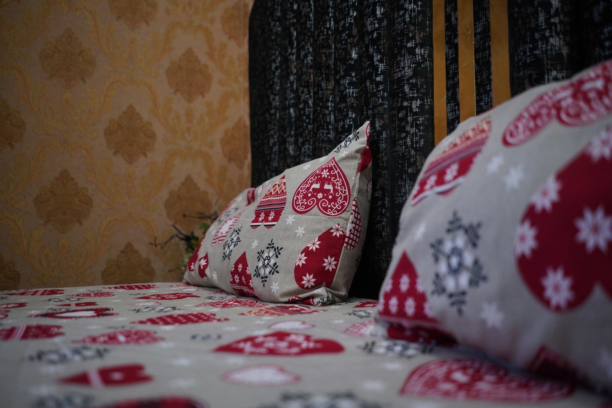 Decorative pillows with floral patterns on a bed against a patterned wall.