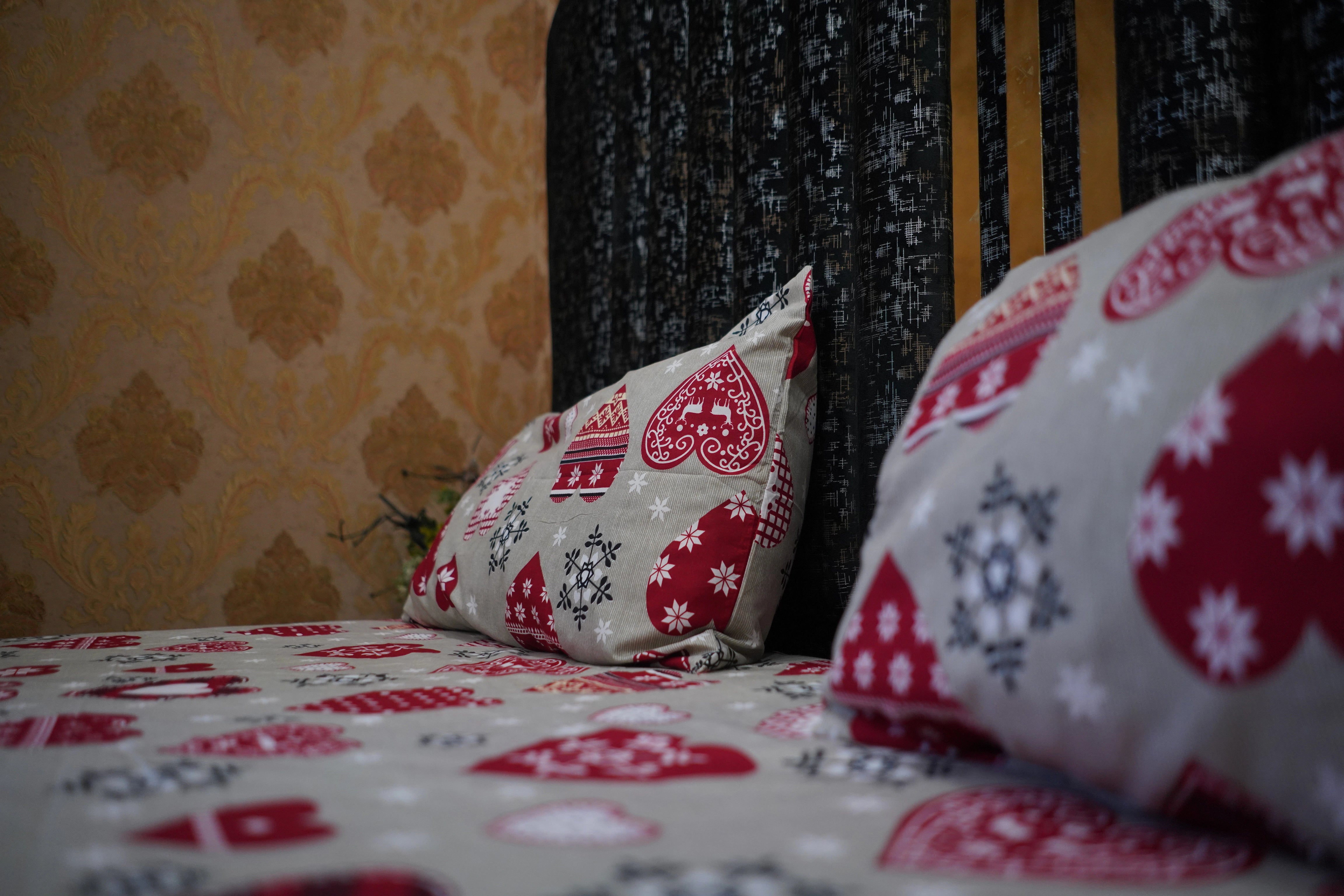 Decorative pillows with floral patterns on a bed against a patterned wall.
