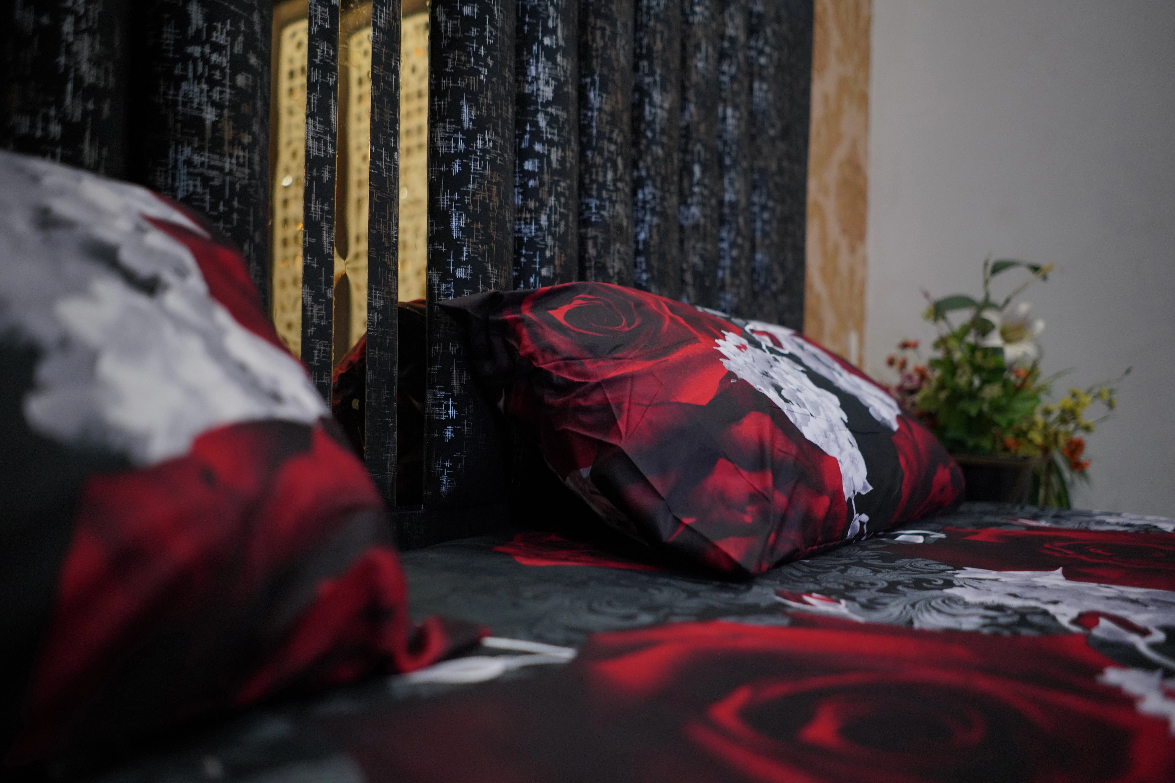 Decorative pillows with red and black rose patterns on a bed.