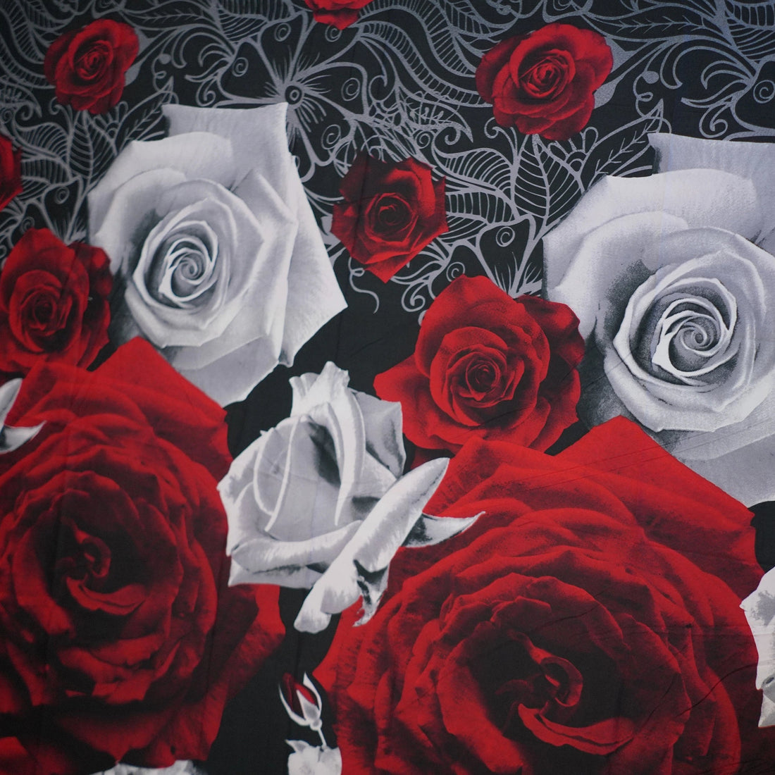 Bedding set with red roses on a bed in a bedroom setting.