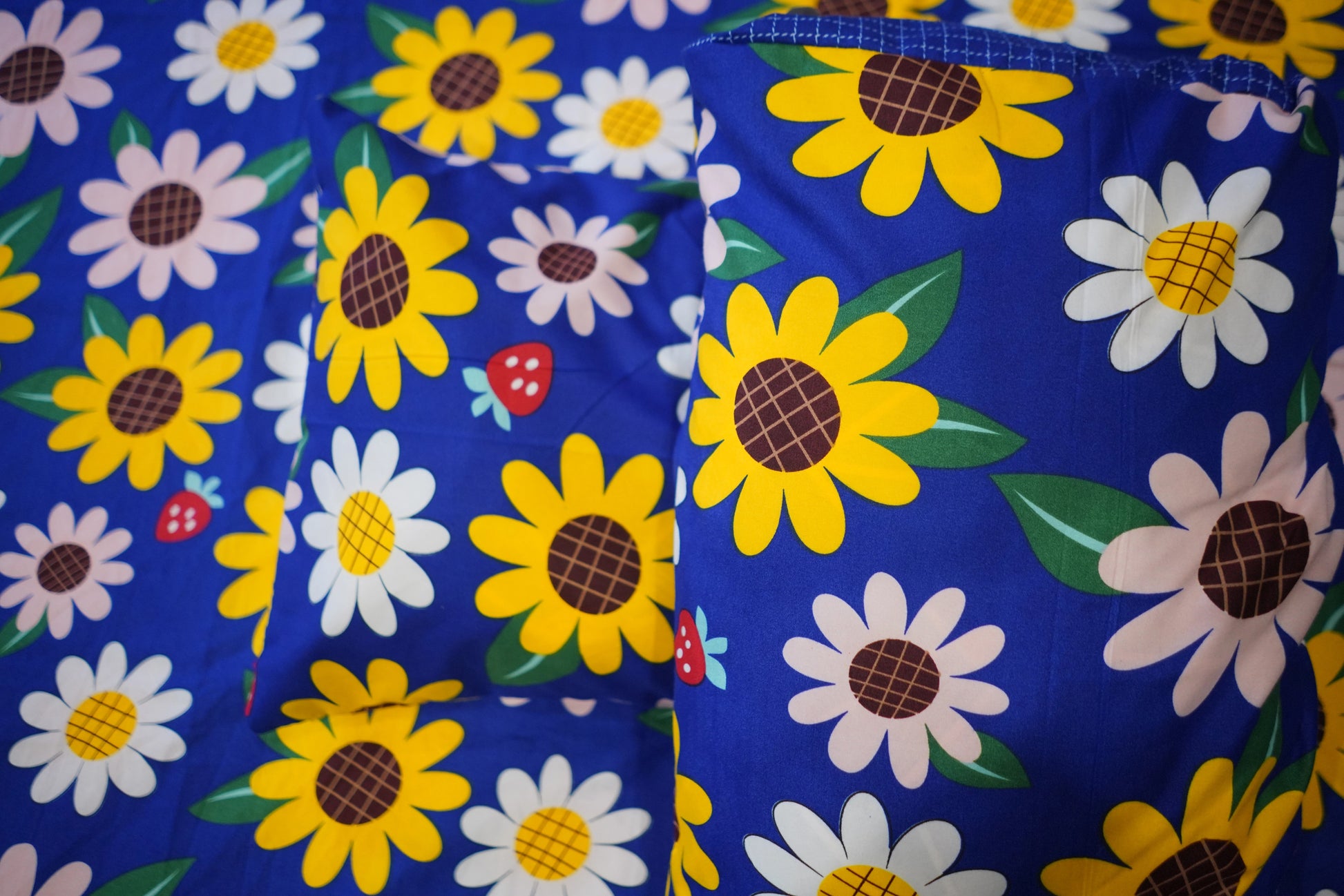 Floral patterned fabric with sunflowers and daisies on a blue background