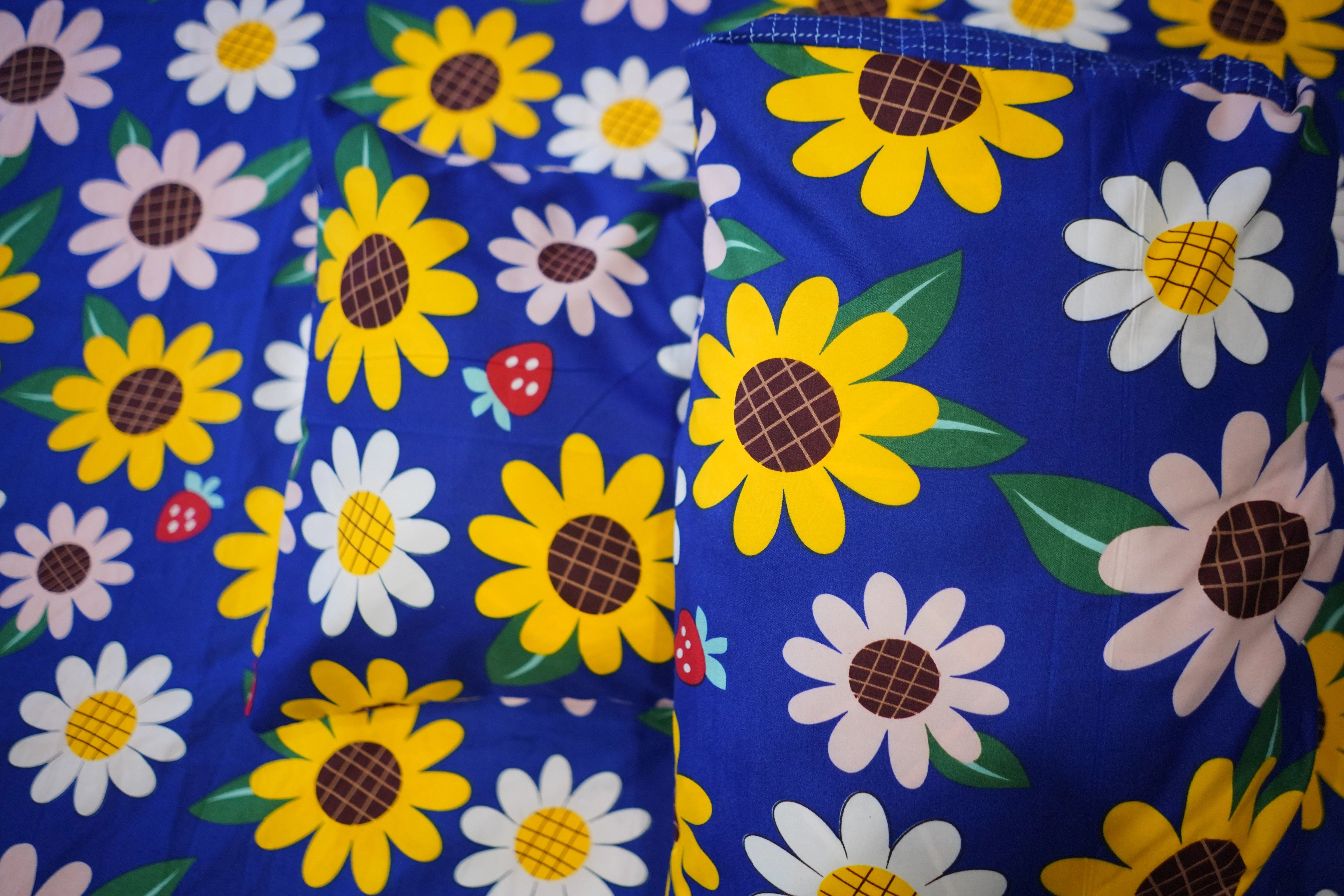 Floral patterned fabric with sunflowers and daisies on a blue background
