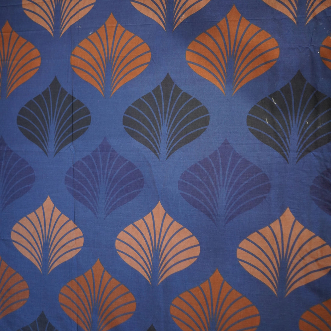 Blue and orange patterned bedding set on a bed in a bedroom with side tables and decor.