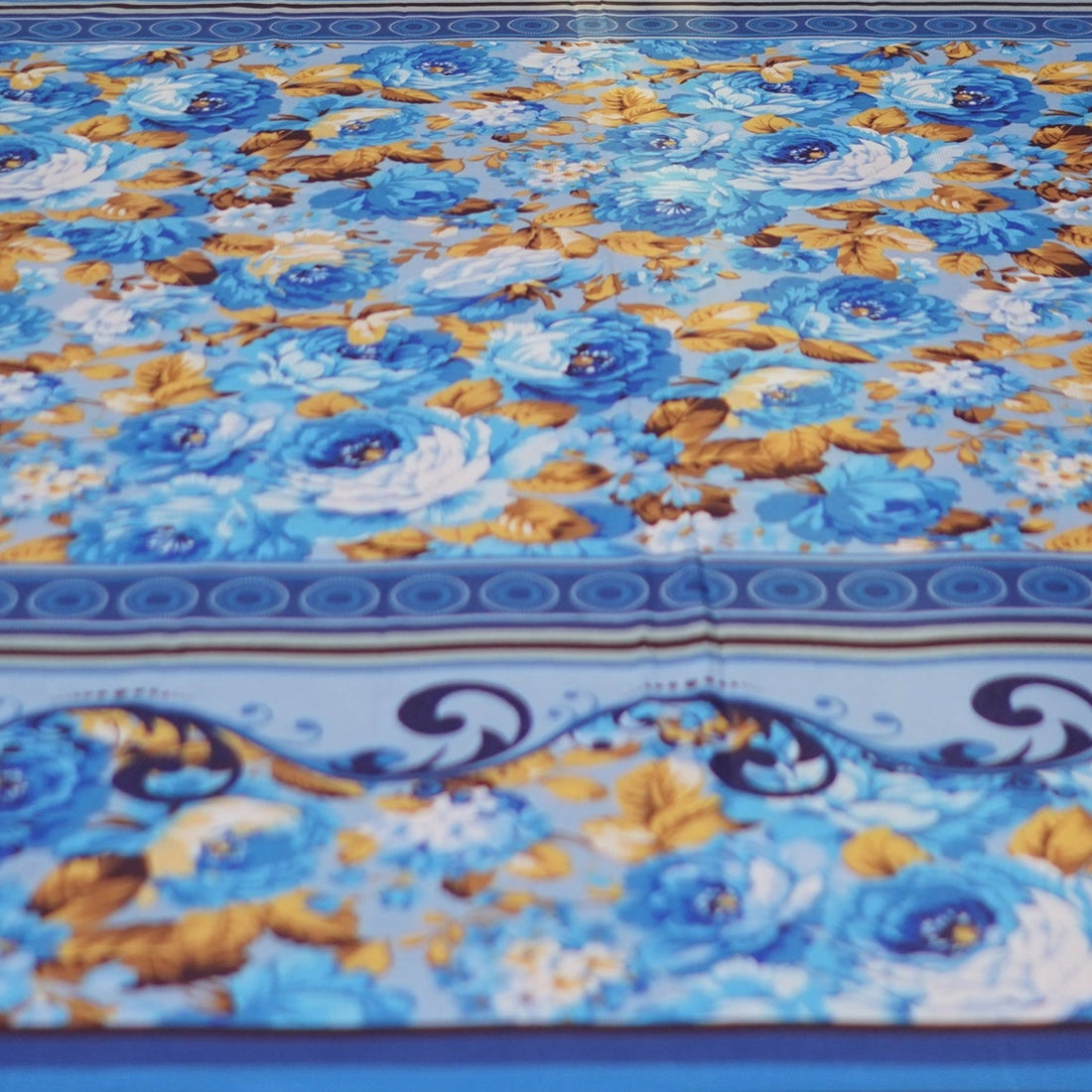 Blue floral patterned bedspread on a bed with matching pillows in a bedroom setting.