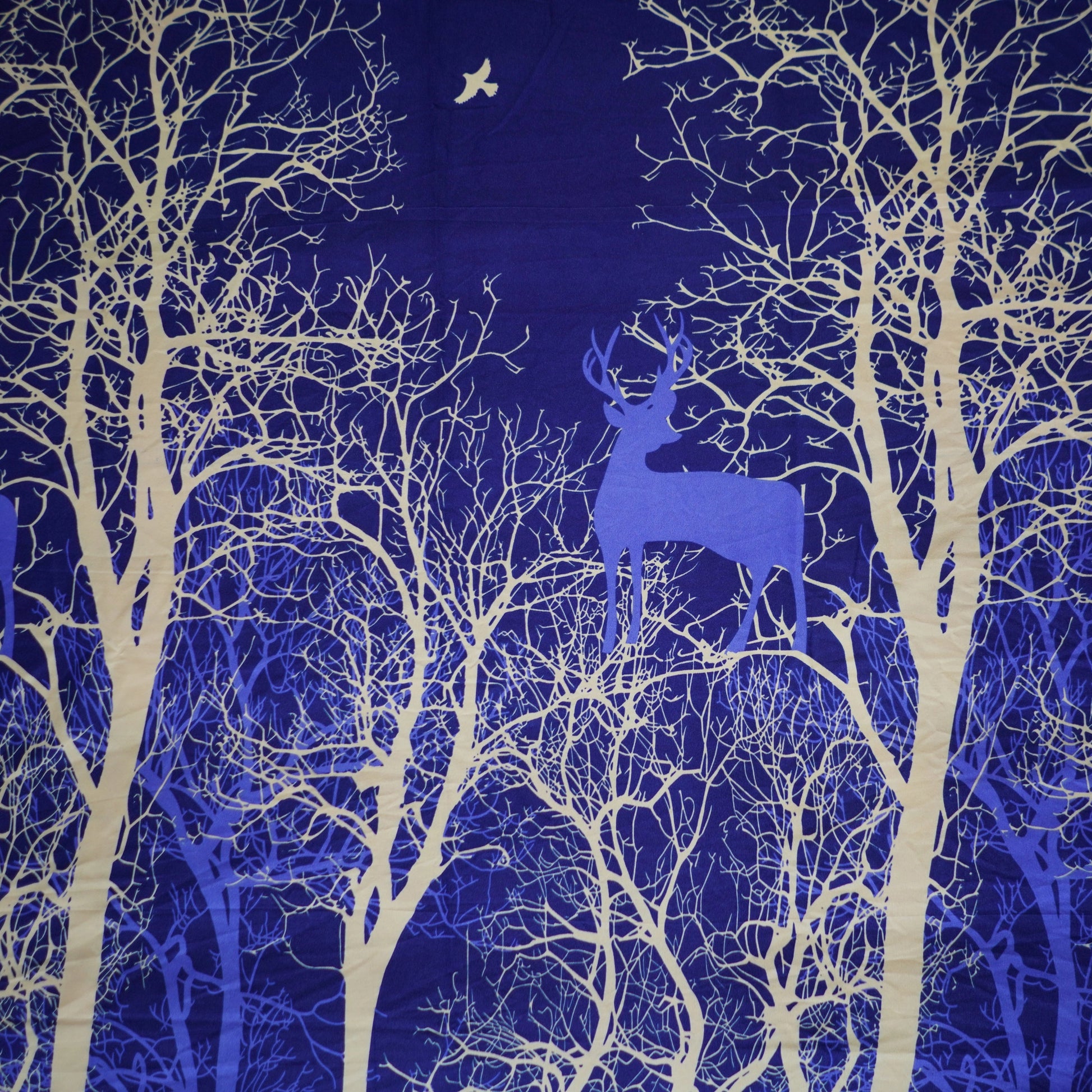 Silhouettes of deer and trees against a dark blue night sky with stars.