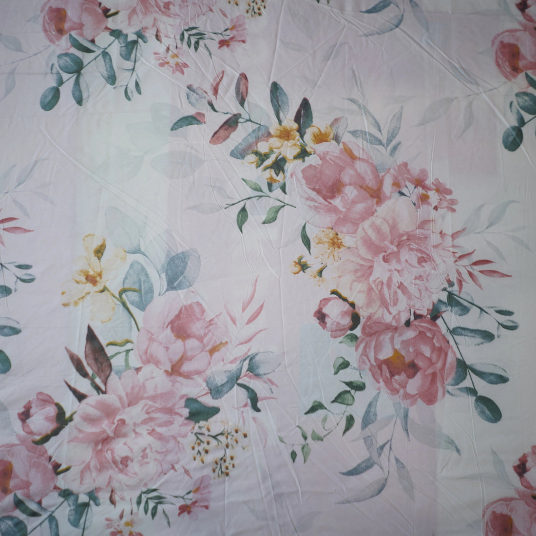 Floral bedding set on a bed in a room with a lamp and window.