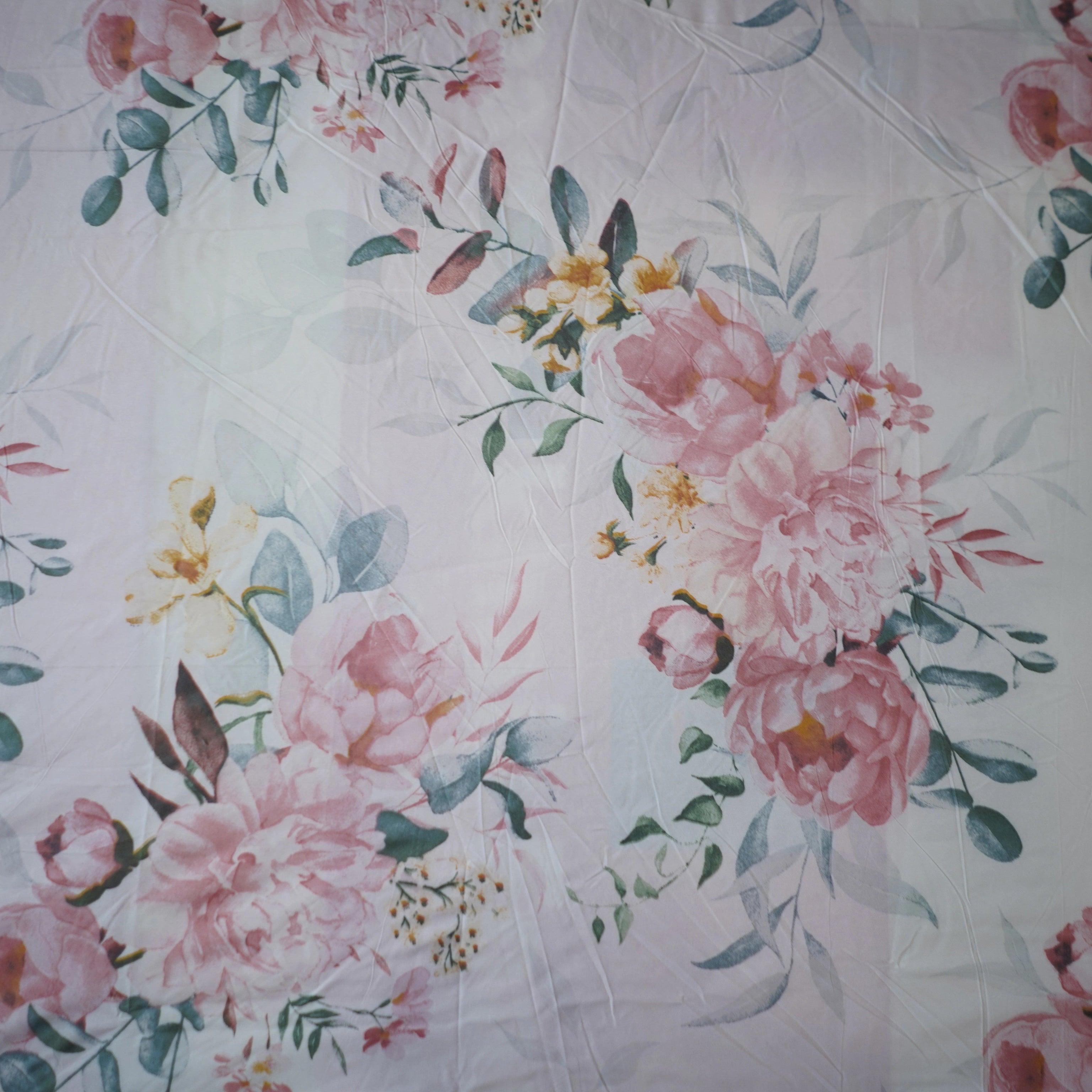 Floral patterned fabric with pink flowers and green leaves on a white background