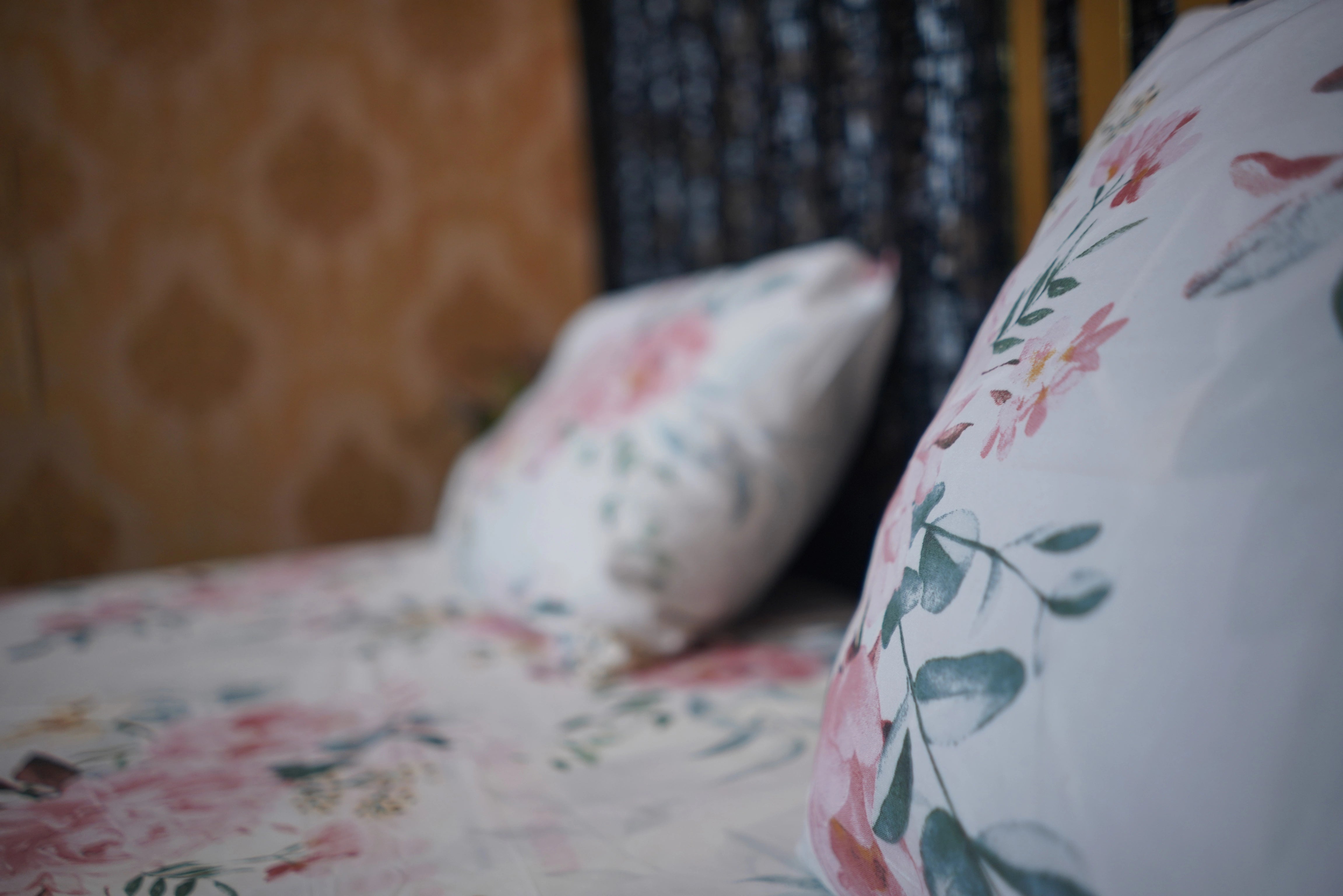 Floral-patterned cushions on a bed with a blurred background