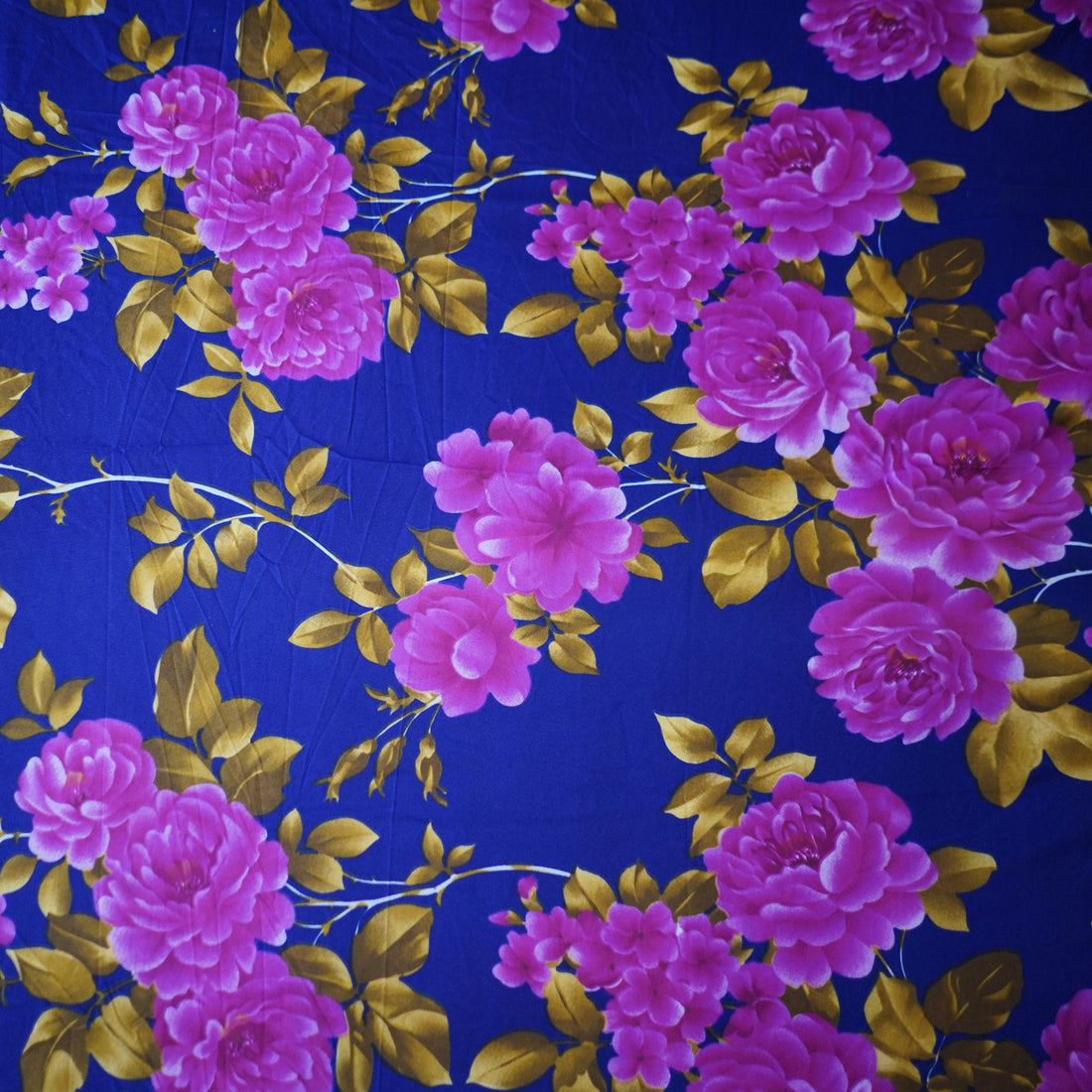Floral bedding set with pink flowers on a blue background in a bedroom setting.
