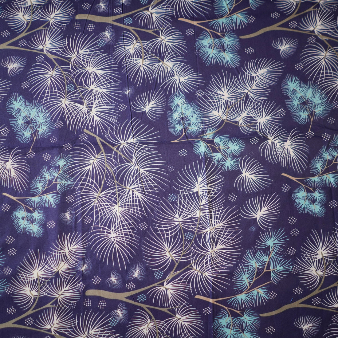 Blue floral patterned bedding set on a bed with a lamp and plant in the background.