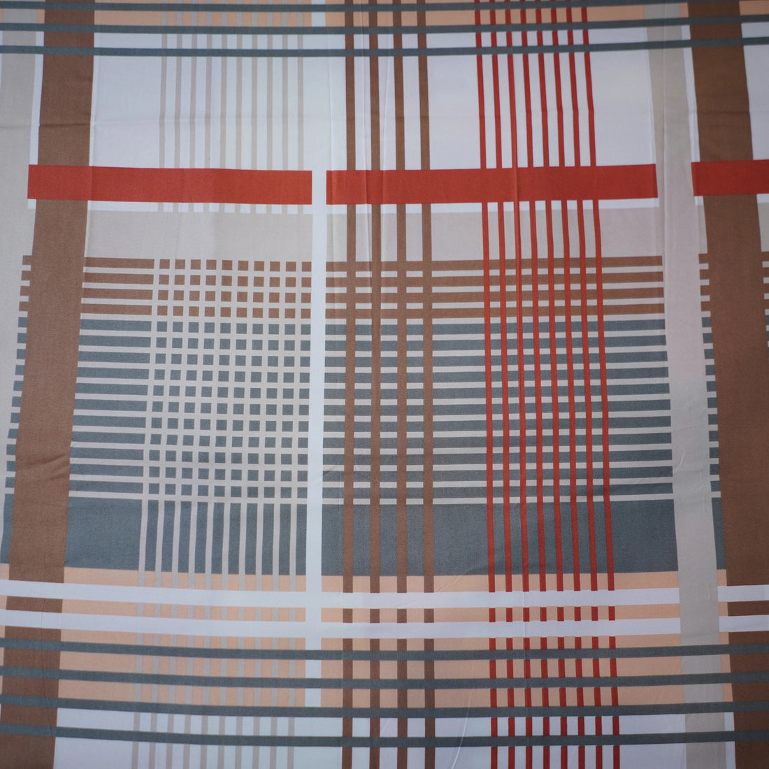 Plaid patterned bedspread on a bed with matching pillows in a bedroom setting.