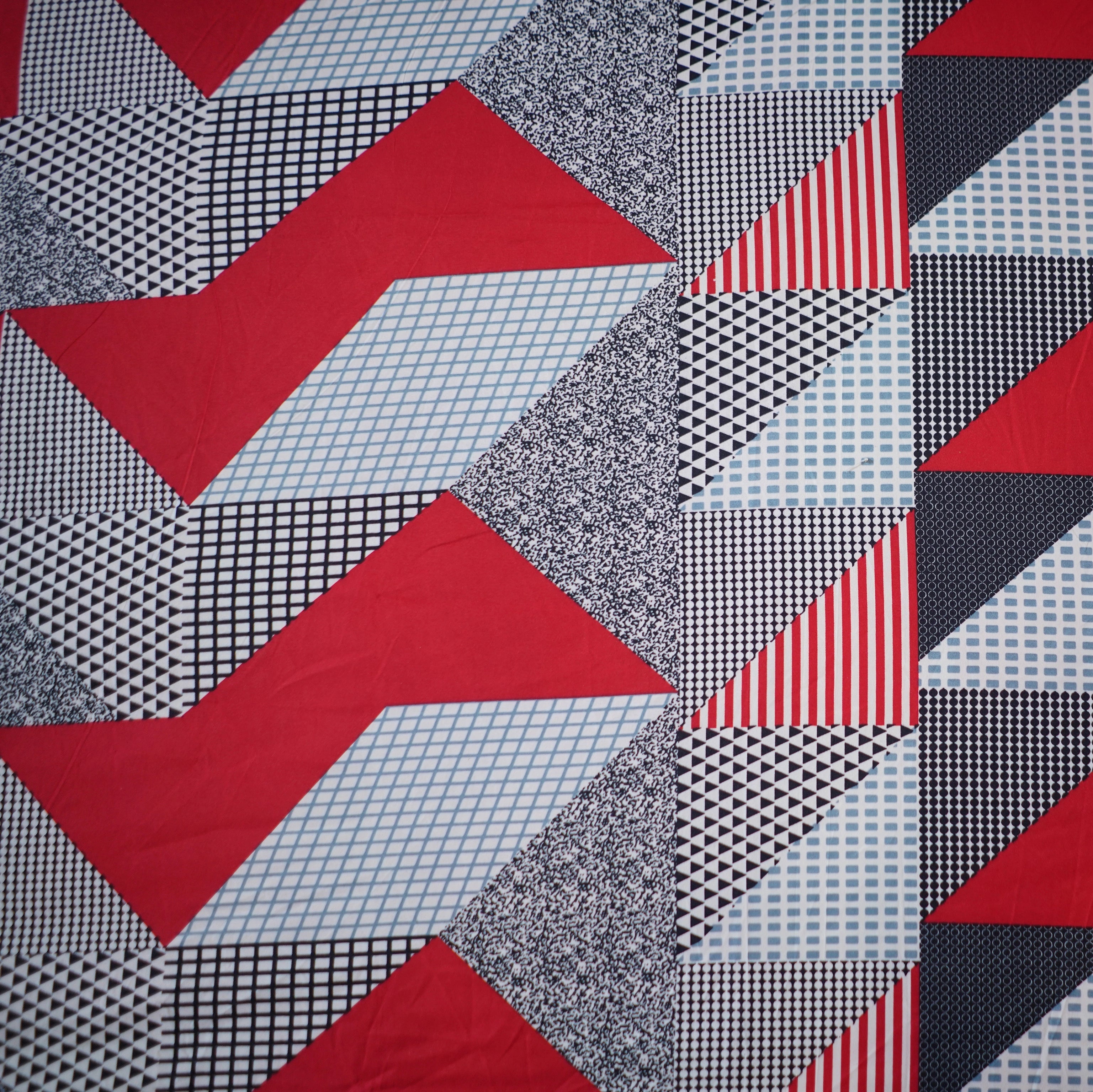 Quilt with geometric pattern of red, black, and gray triangles.