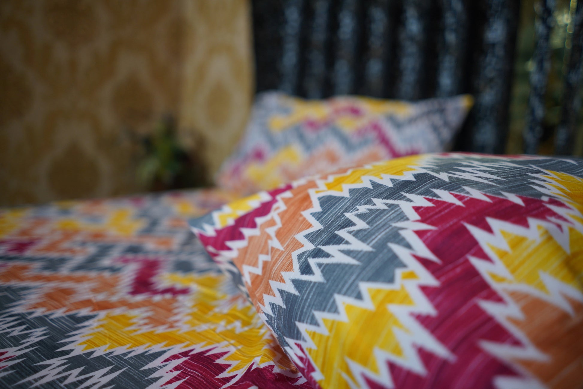 Colorful geometric-patterned pillows on a bed with a blurred background