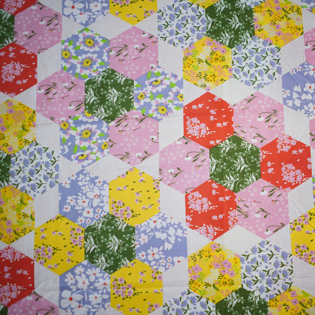 Floral quilt set on a bed in a bright bedroom with large windows.