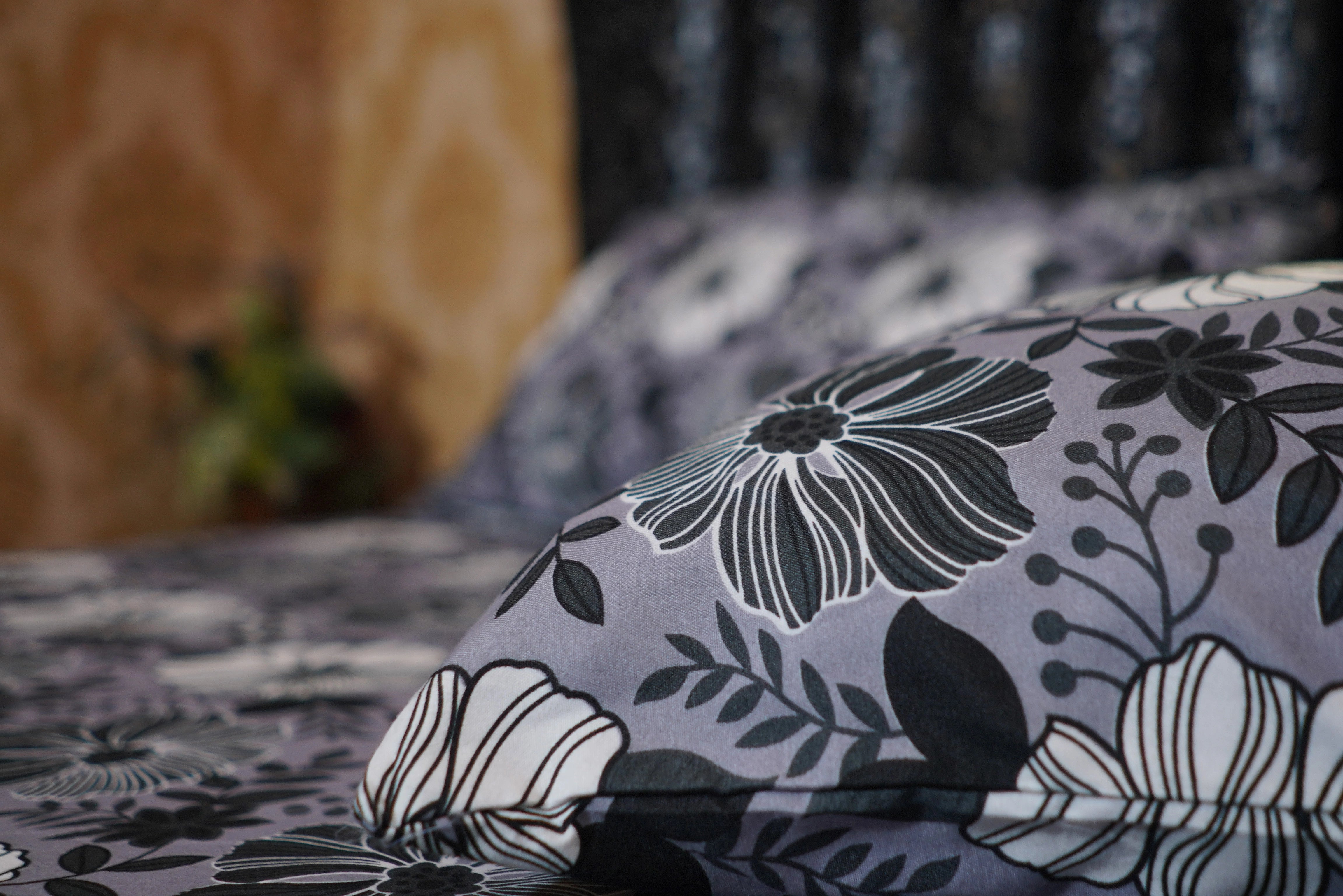 Floral patterned pillow on a bed with a blurred background