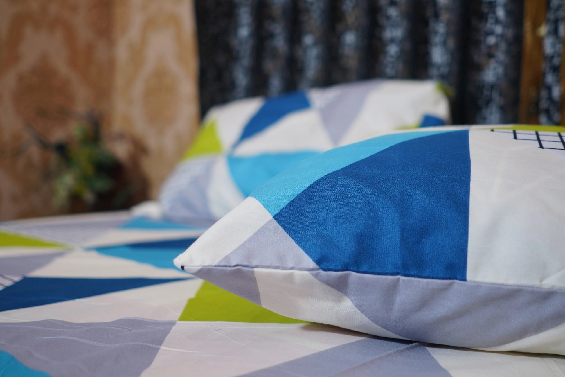 Colorful geometric-patterned bedspread on a bed with pillows.