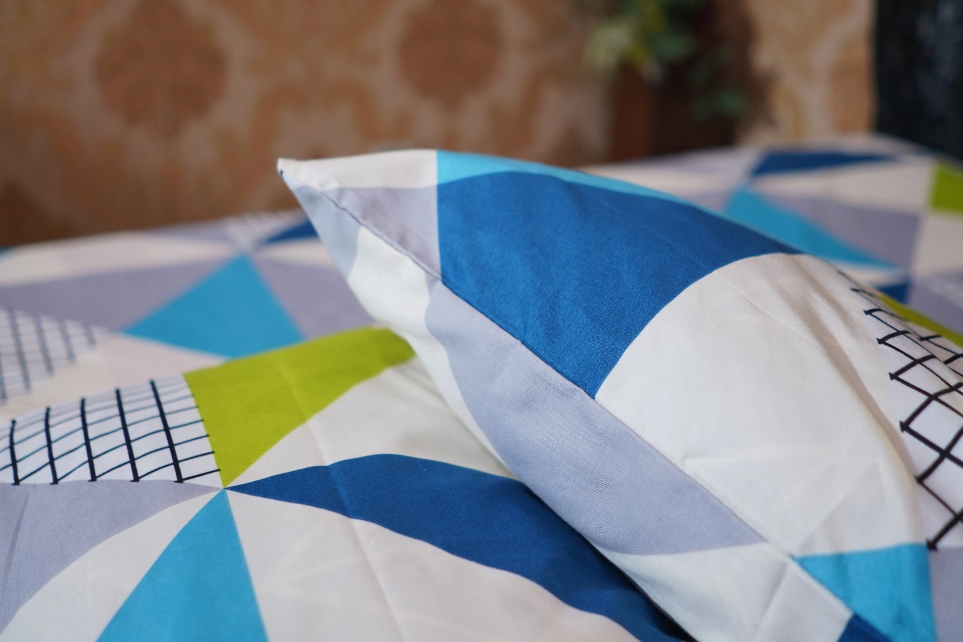 Colorful geometric-patterned pillow on a bed with a blurred background