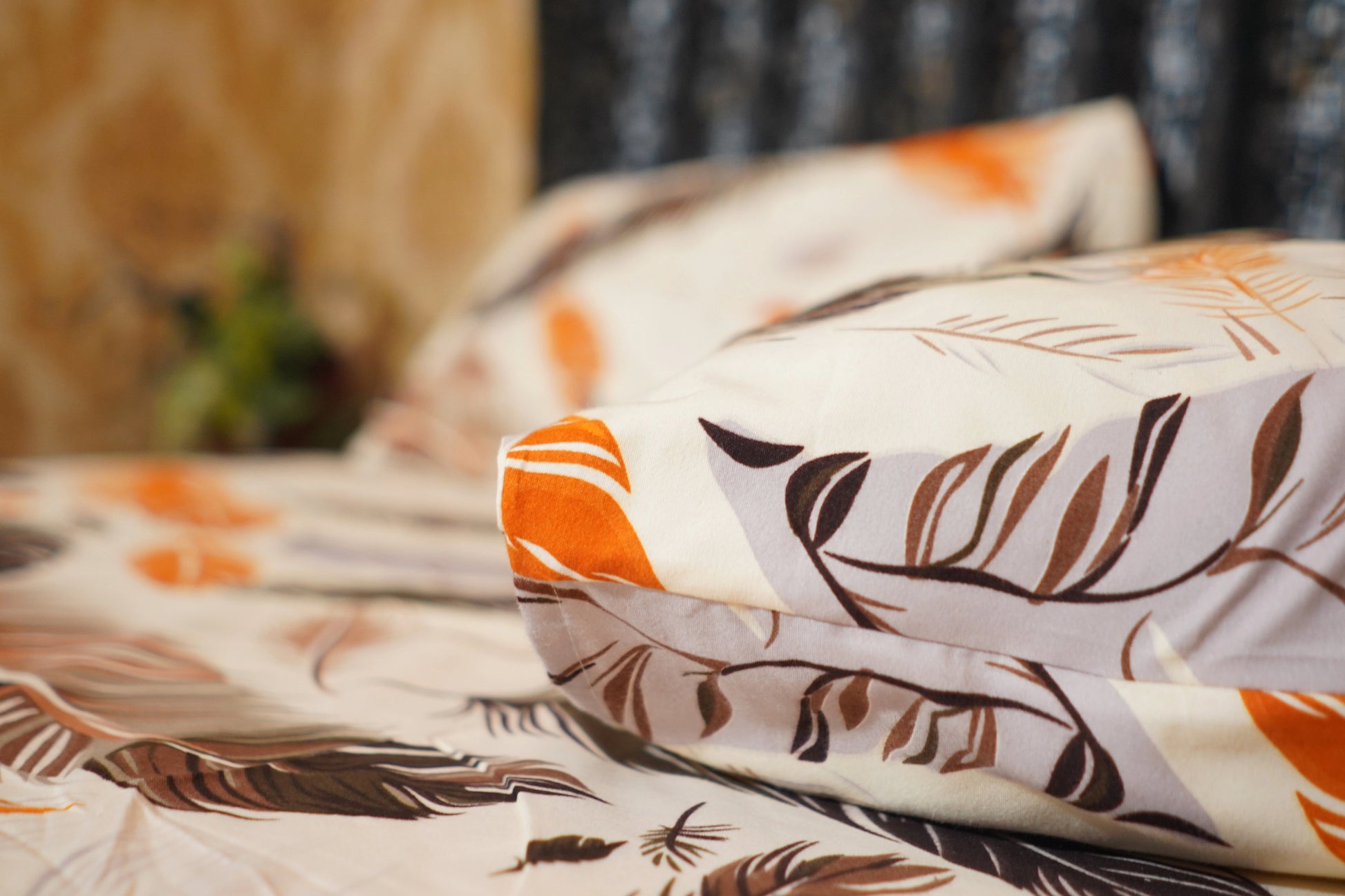 Floral-patterned fabric with orange and brown colors on a bedspread.
