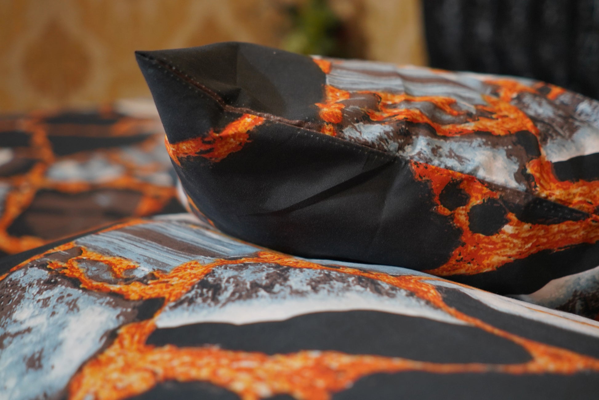Close-up of a fabric with lava-like pattern in orange, black, and gray.