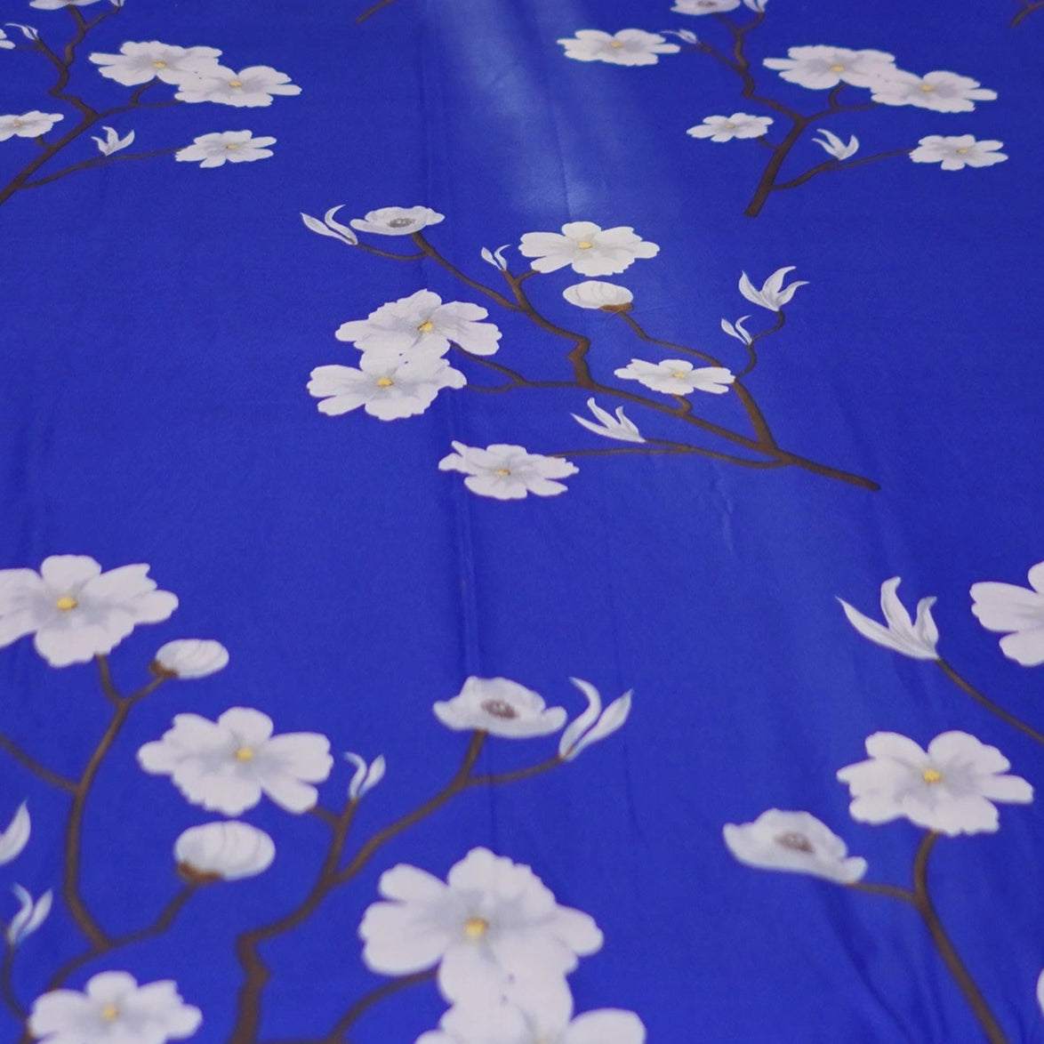 Bed with blue floral bedspread and black headboard against a patterned wall.