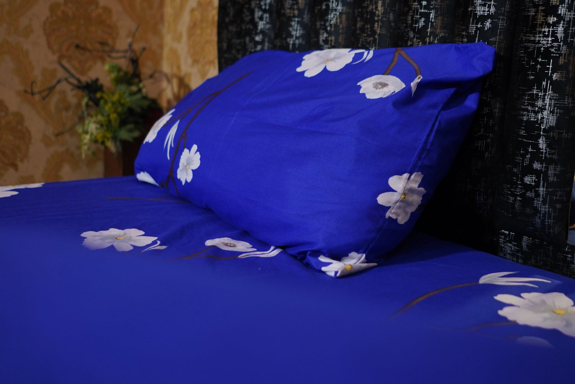 Blue floral bedspread on a bed with a blurred background