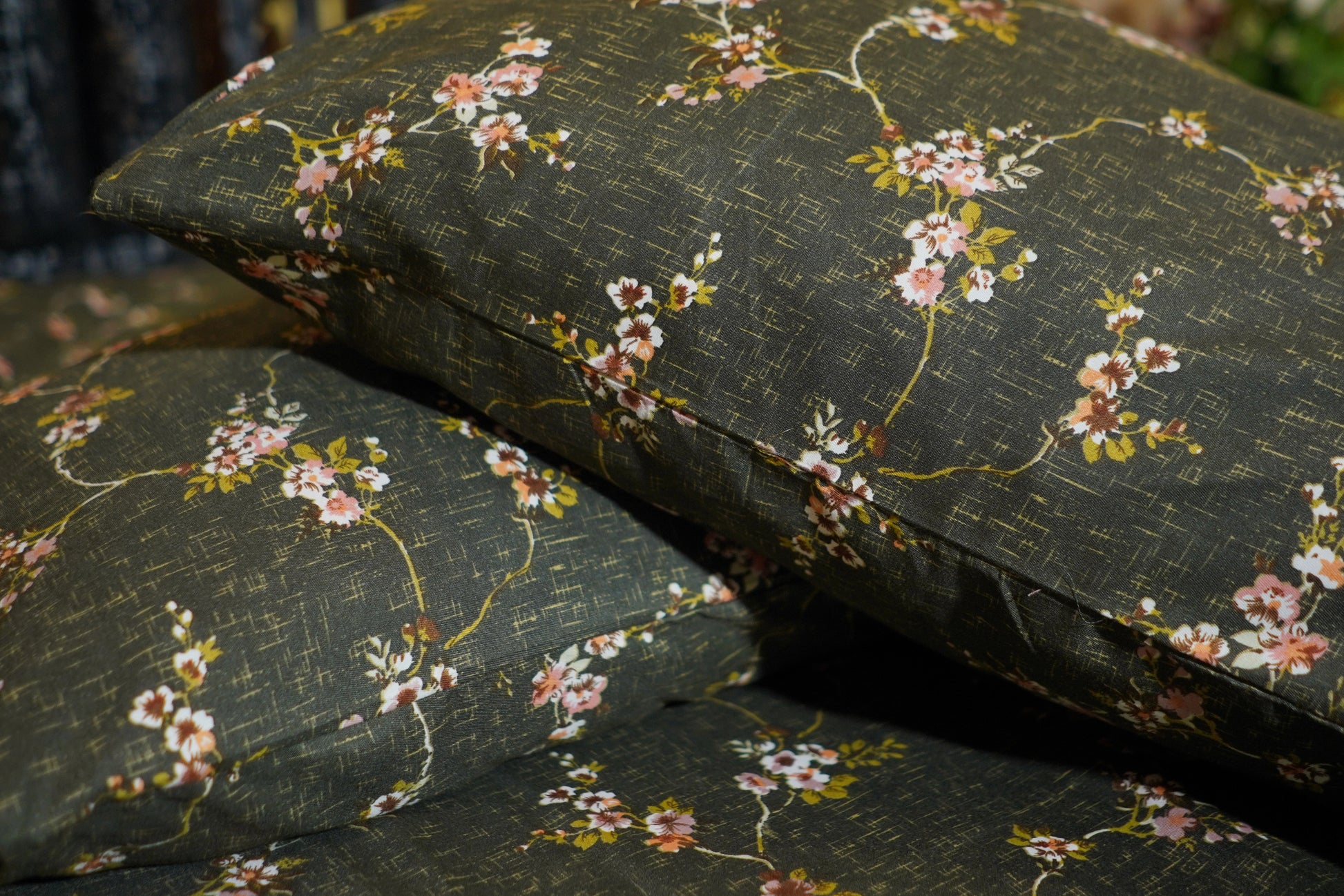 Floral-patterned cushions on a dark green fabric background