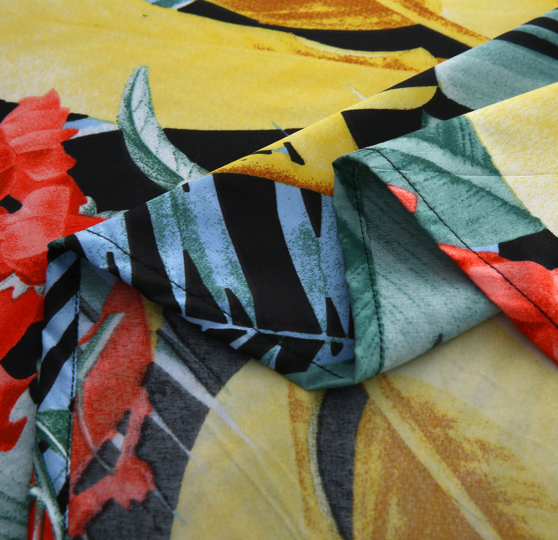 Tropical leaf patterned comforter set on a bed in a room with a plant and lamp.
