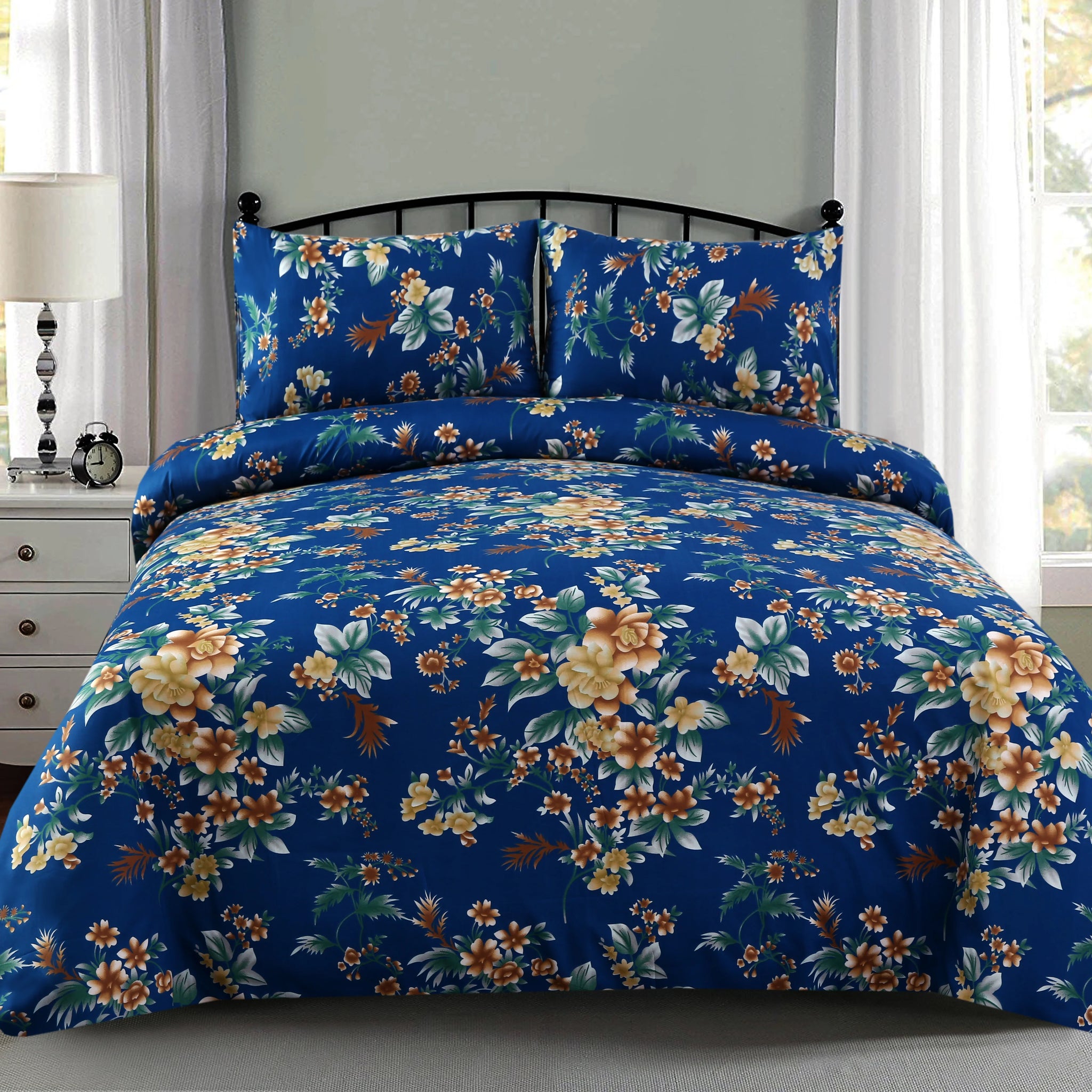 Floral bedding set on a bed in a bedroom with a lamp and clock on a nightstand.