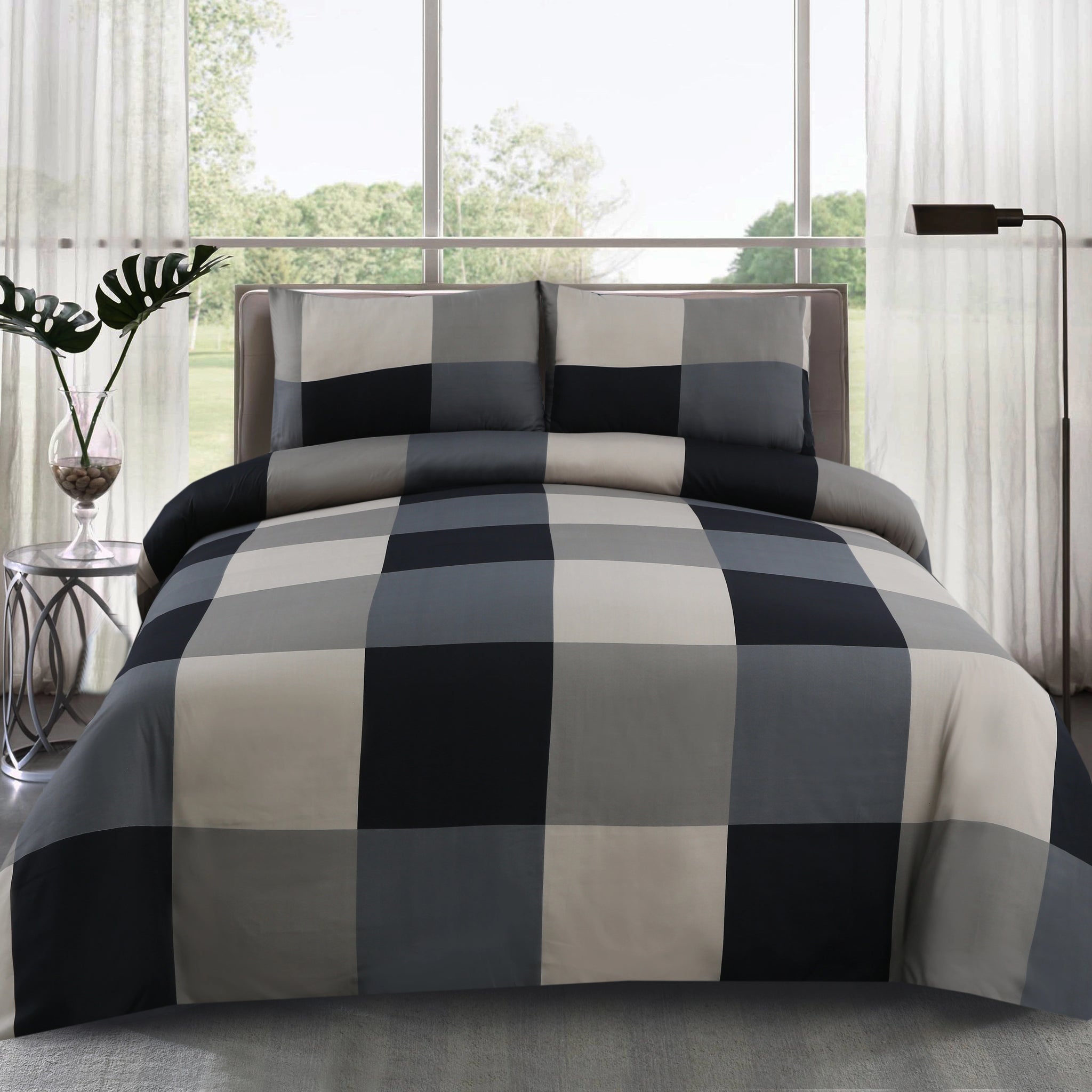 Checkered bedspread on a bed in a bright room with large windows.