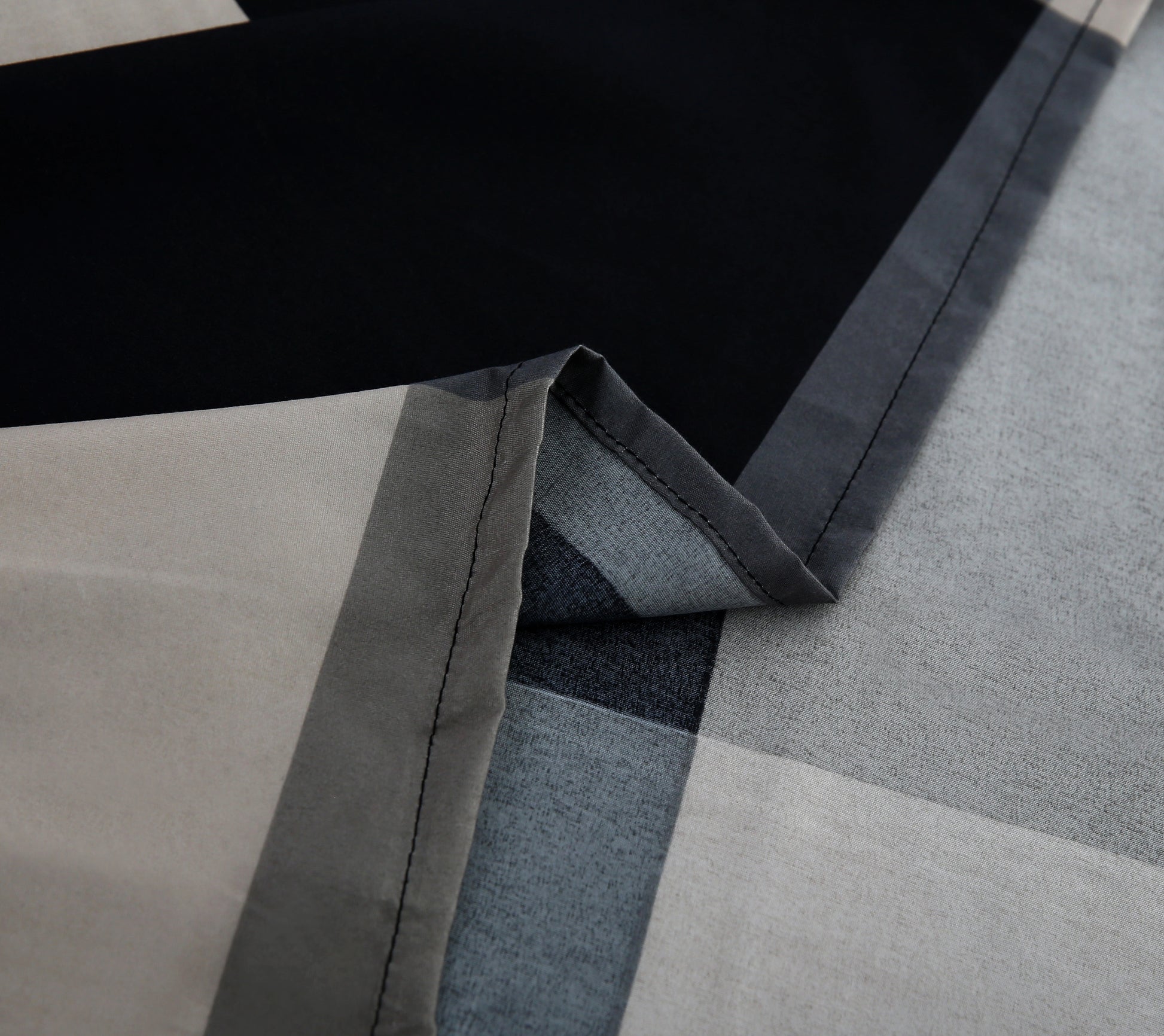 Close-up of a geometric-patterned rug with black, gray, and beige colors.