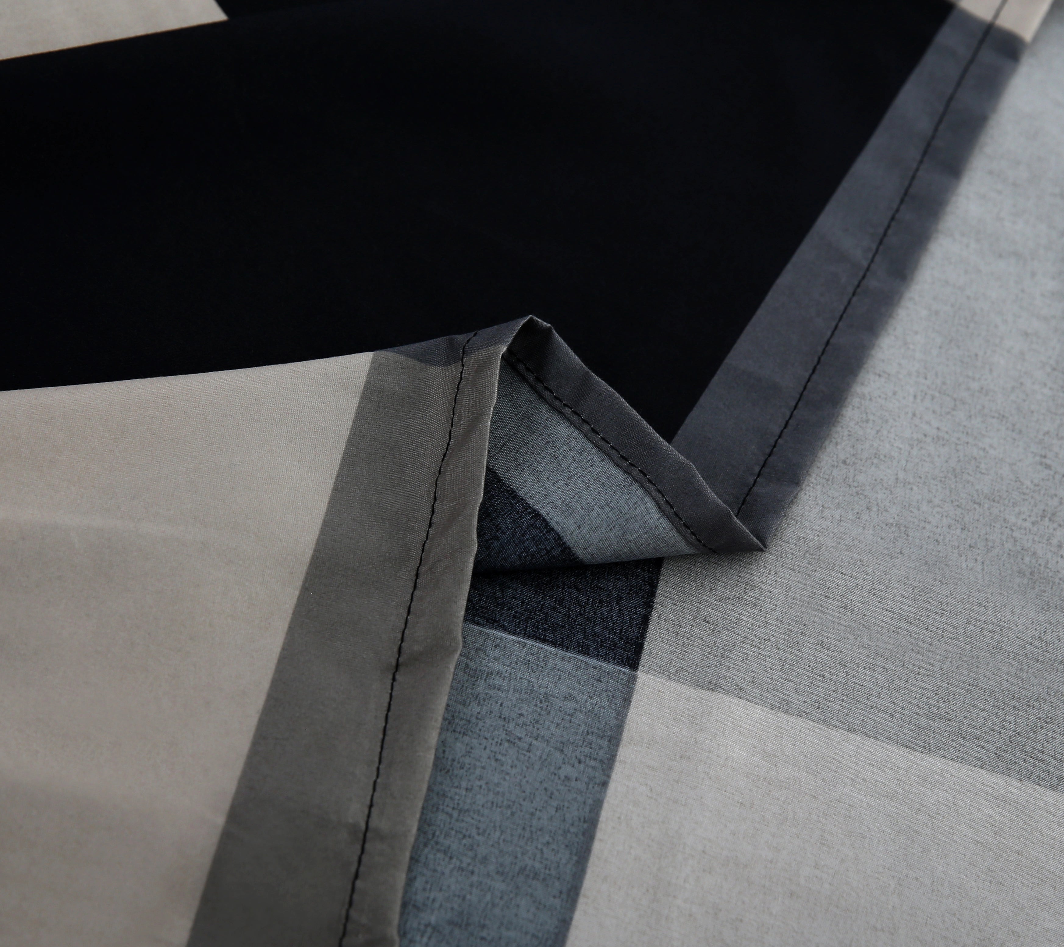 Close-up of a geometric-patterned rug with black, gray, and beige colors.