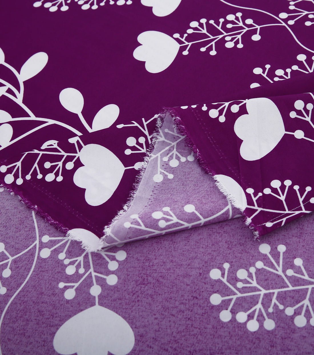 Purple floral bedding set on a bed in a bedroom with pink decor.
