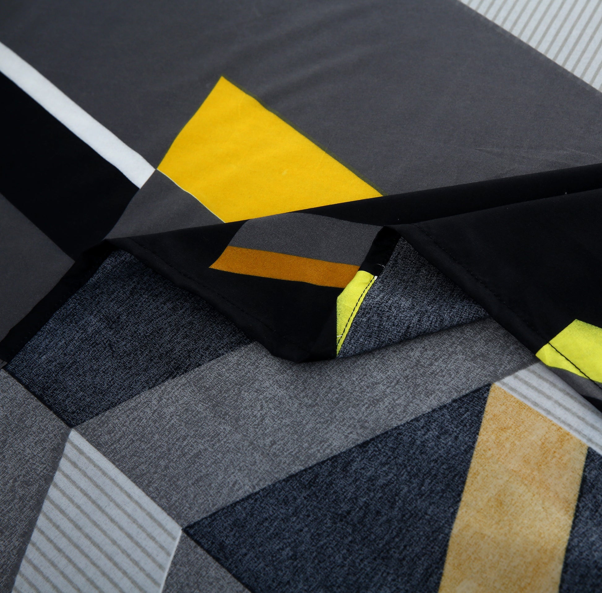 Close-up of a fabric with geometric pattern featuring black, gray, yellow, and white.