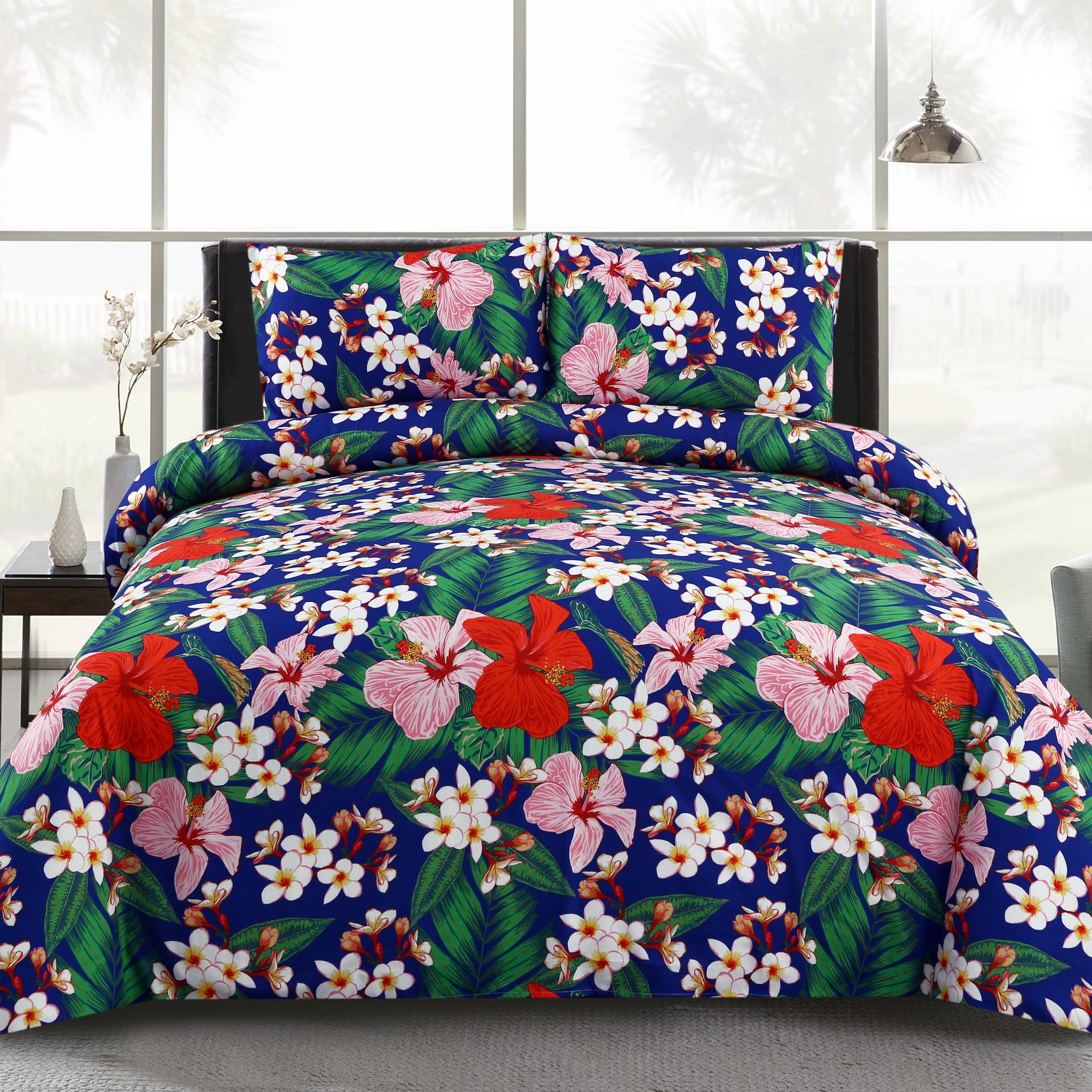Floral bedding set on a bed in a room with a gray chair and white walls.