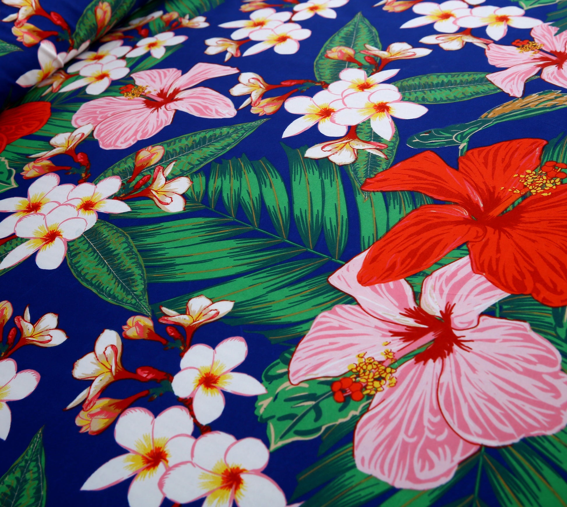 Tropical floral pattern with red, pink, and white flowers on a blue background
