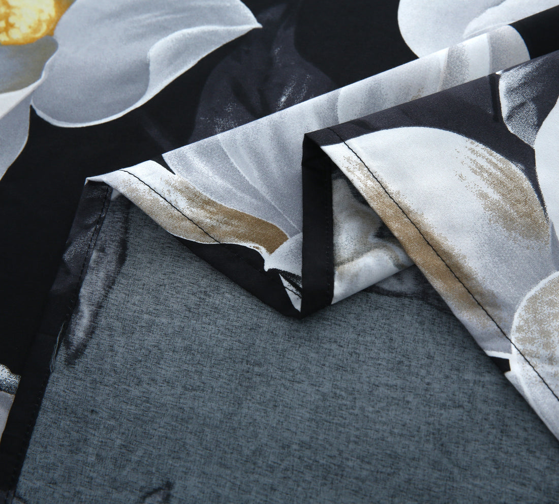 Floral bedding set with white flowers on a black background in a bedroom setting.